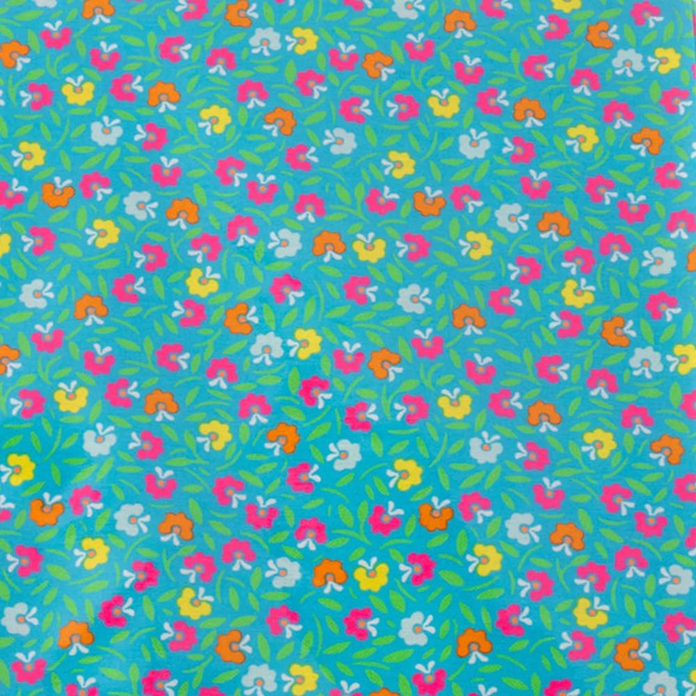 A folded cotton enduit sheet from Petit Pan Paris, featuring a vibrant turquoise background with a colorful floral and leaf pattern in pink, yellow, orange, and white, wrapped with a white paper band.