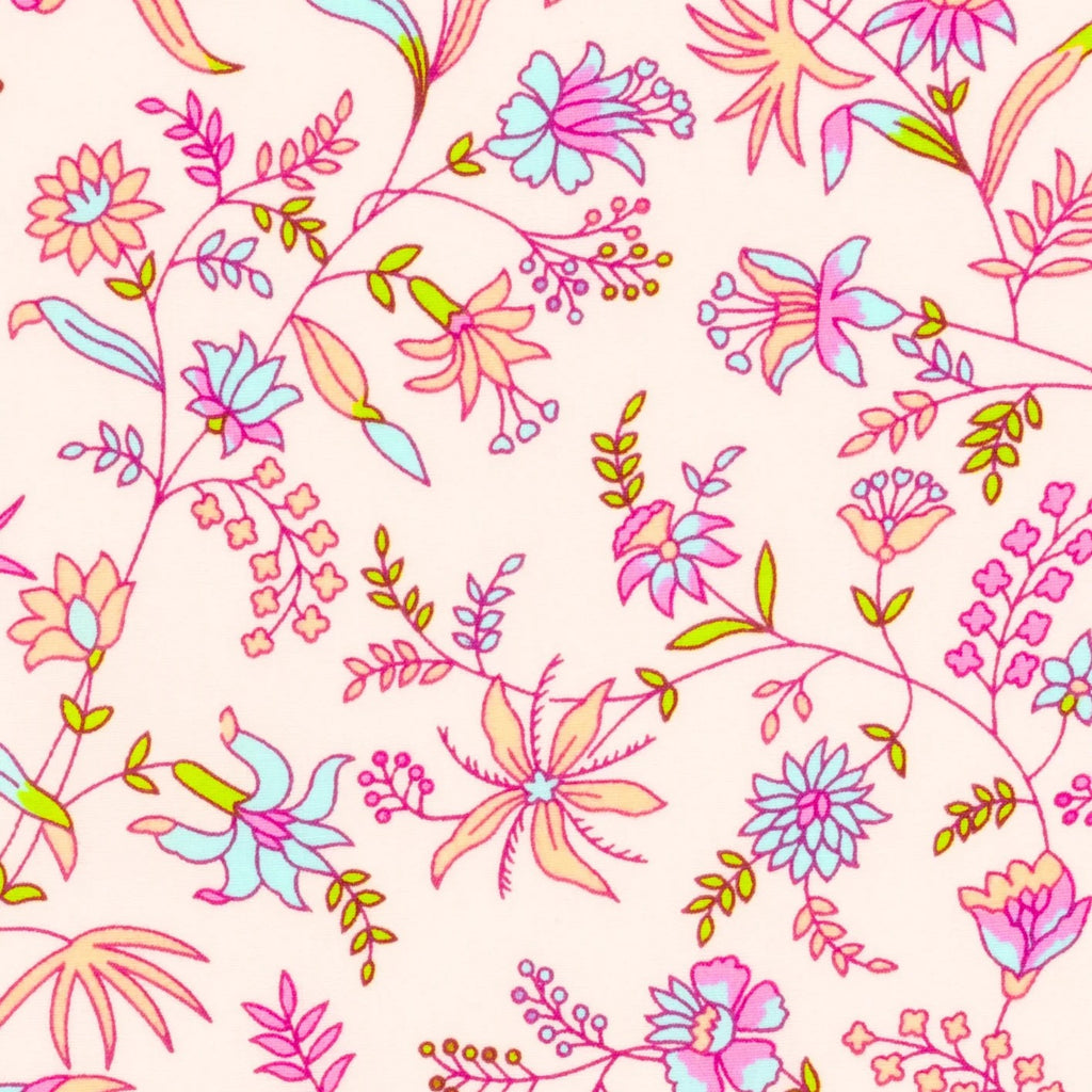 A folded cotton blanket with a colorful floral pattern on a light pink background, wrapped in a light blue paper band labeled 'Petit Pan Paris'. Oilcloth Coupon | Petit Pan | Saholy Sand