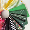 Collection of colorful fabric swatches with patterns, including green, black, and white designs, on a white background.